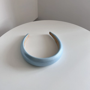 Close-up of padded light blue headband with pearl luster finish on white display tray