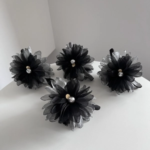Detail of chiffon flower hair claws with grey pearls and golden heart charms on white stage