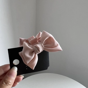 Detail of a cute light pink silk bow hair claw clip for small ponytail styling