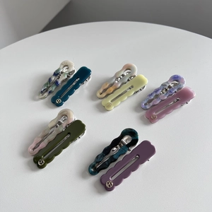 Detail of colorful acetate wavy and teardrop hair clips with elegant marble texture