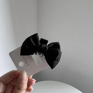 Close-up of black satin bow hair claw clip showing fabric texture and resin teeth