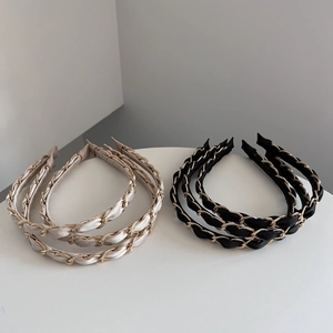 Detail of satin fabric woven with gold metal chain headbands in black and champagne colors