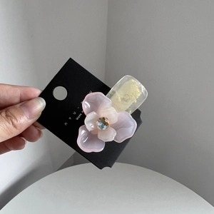 Dettaglio molletta per capelli a fiore rosa con gemma su cartoncino nero da esposizione