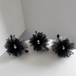 Detailed close-up of grey and black layered fabric flower hair clips with pearl center