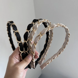 Detailed close-up of woven chain hairband in black and beige with gold metal link details