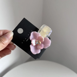 Dettaglio di un fermaglio per capelli a fiore rosa con strass su cartoncino