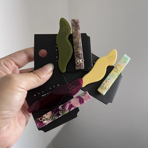 Elegant wave and rectangular acetate hair clips set with golden bow accents