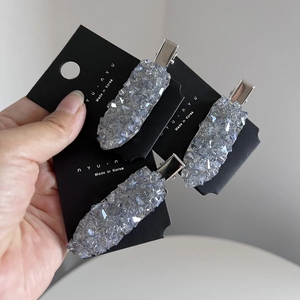 Close-up of three silver duckbill hair clips with sparkling crystal rhinestones detail