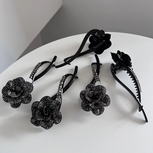 Elegant black camellia hair clips with rhinestones and metal details on white background
