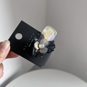 Dettaglio di una clip per capelli a fiore 3D in resina con cristallo su cartoncino