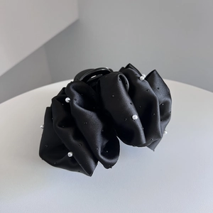 Detail of elegant black pleated satin hair claw clip with pearls and small rhinestones