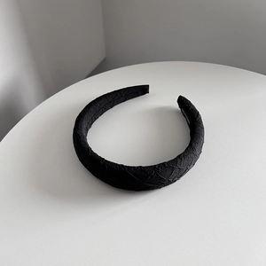Détail d'un bandeau large noir fait main avec texture en tissu jacquard et logo