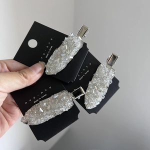 Close-up of three silver hair clips with sparkling crystals on a black display card