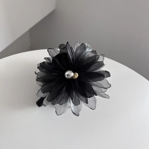 Close-up of translucent black and grey layered tulle petal hair claw with pearl detail