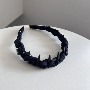 Détail d'un serre-tête en tissu bleu marine à pois avec dents antidérapantes noires