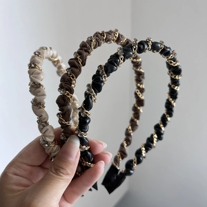 Detail of ruched leather headbands in beige, brown and black with gold chains and crystals