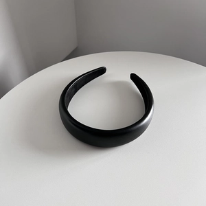Détail du serre-tête rembourré en cuir noir mat au design minimaliste et à la texture arrondie