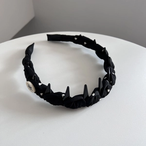 Détail du serre-tête en tissu tressé avec imprimé cœur et pointes style punk