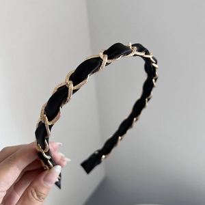 Detail of woven gold metal chain and black satin fabric headband in vintage style