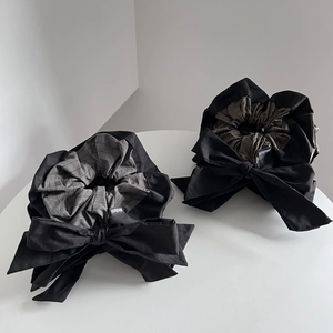Minimalist black and grey striped oversized bow scrunchie on a white pedestal display