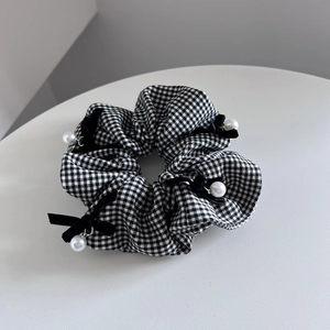 Détail du chouchou à carreaux avec nœuds en velours noir et perles pendantes