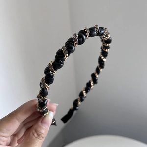 Detail of black pleated leather headband with gold chains and sparkling crystals