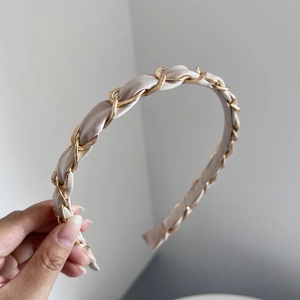 Close-up of champagne satin headband with woven golden chain detail for women