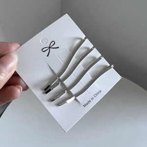 Set of four minimalist silver wavy metal hair clips on a white display card