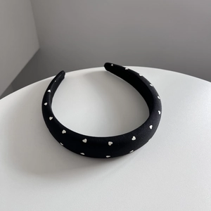 Vue détaillée d'un serre-tête noir rembourré avec motif cœur blanc et texture en tissu