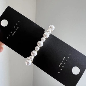 Détail d'une barrette à cheveux élégante avec 10 perles sur une carte noire de luxe