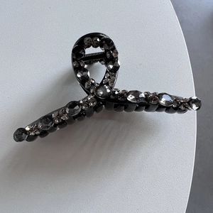 Dettaglio del fermaglio per capelli nero con strass grigio fumo scintillanti incastonati