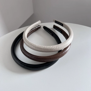 Gros plan de serre-têtes en cuir texturé de couleurs beige, marron et noir