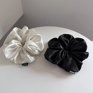 Set of two satin scrunchies in black and cream featuring elegant camellia flower patterns