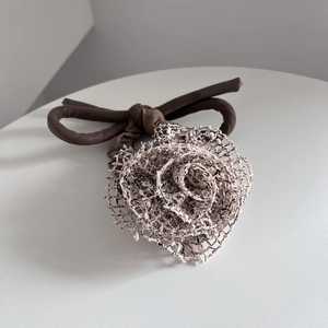 Détail de l'élastique à cheveux avec fleur en maille faite main et ruban marron élégant