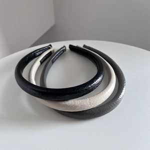 Détail de trois serre-têtes larges en similicuir PU noir, beige et gris foncé élégants