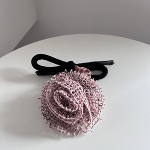 Gros plan d'un chouchou rose en forme de rose avec des bords noirs et un élastique épais