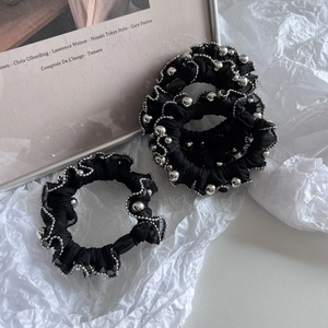 Close-up of black scrunchies with silver beaded trim and pleated texture in macro view