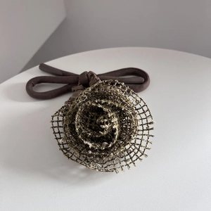 Vue détaillée d'une rose en maille dorée sur un élastique à cheveux marron foncé