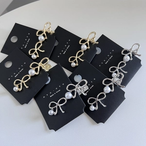 Elegante Haarklammern mit Schleifen in Gold und Silber und weißen Perlen auf Displaykarte