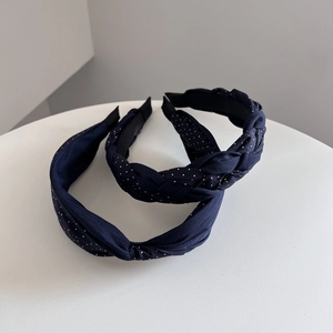 Close-up of navy blue polka dot braided and knotted headbands set on a white tray