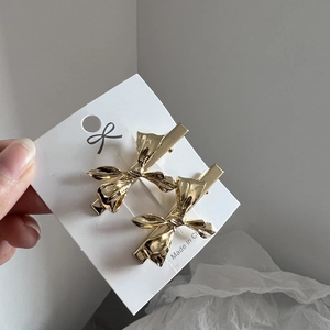 Set aus zwei goldenen Metall-Schleifen-Haarspangen auf einer Displaykarte für Styling