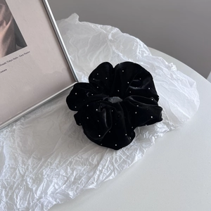 Close-up of black velvet scrunchie with silver sparkles on elegant white background