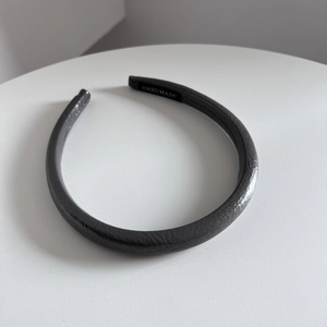Gros plan d'un serre-tête en cuir noir fait main avec texture grainée et étiquette