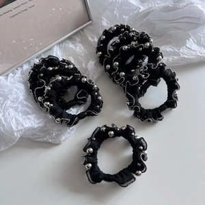 Detail of black pleated mesh scrunchie with silver beaded trim for vintage hair styling