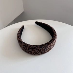 Dettaglio del cerchietto in velluto leopardato su supporto espositivo bianco