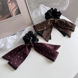 Detail of large bow hair ties with heart patterns in dark brown and burgundy colors