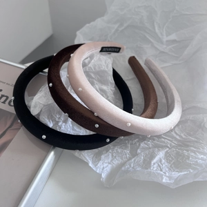 Close-up of three velvet pearl headbands in black, brown and pink with handmade label
