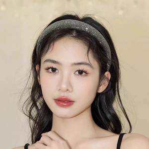 Front view of model wearing a dark gray padded headband with shiny rhinestones