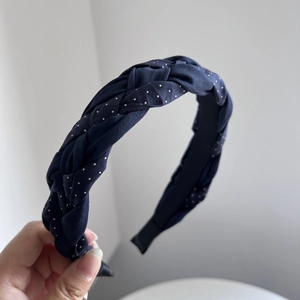 Detail of navy blue braided headband with white polka dots and soft fabric texture