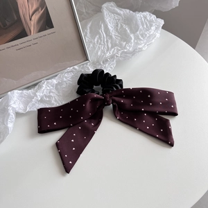 Detail of burgundy bow scrunchie with white heart print on a minimalist white surface